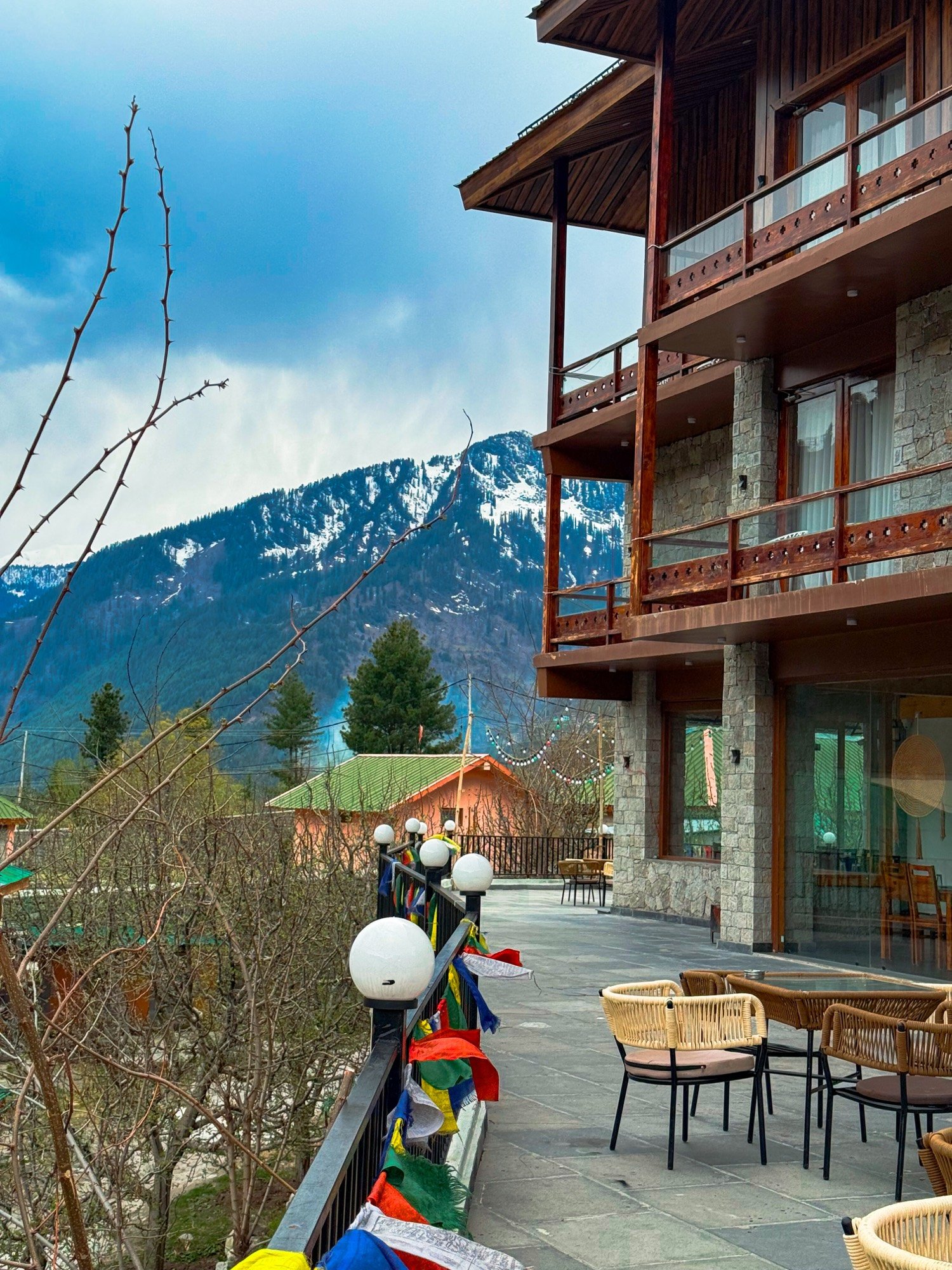 Rigzin House with prayer flags and snow peaks behind